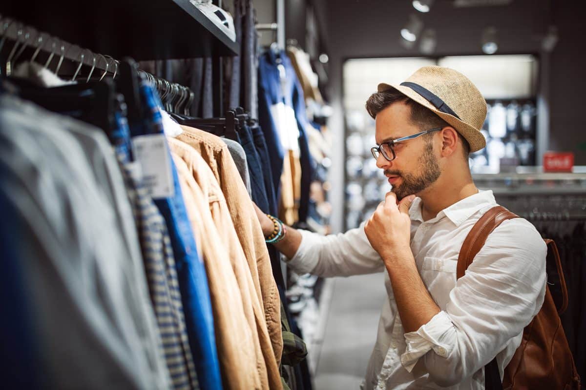 A young adult man browsing clothes in an upscale store
