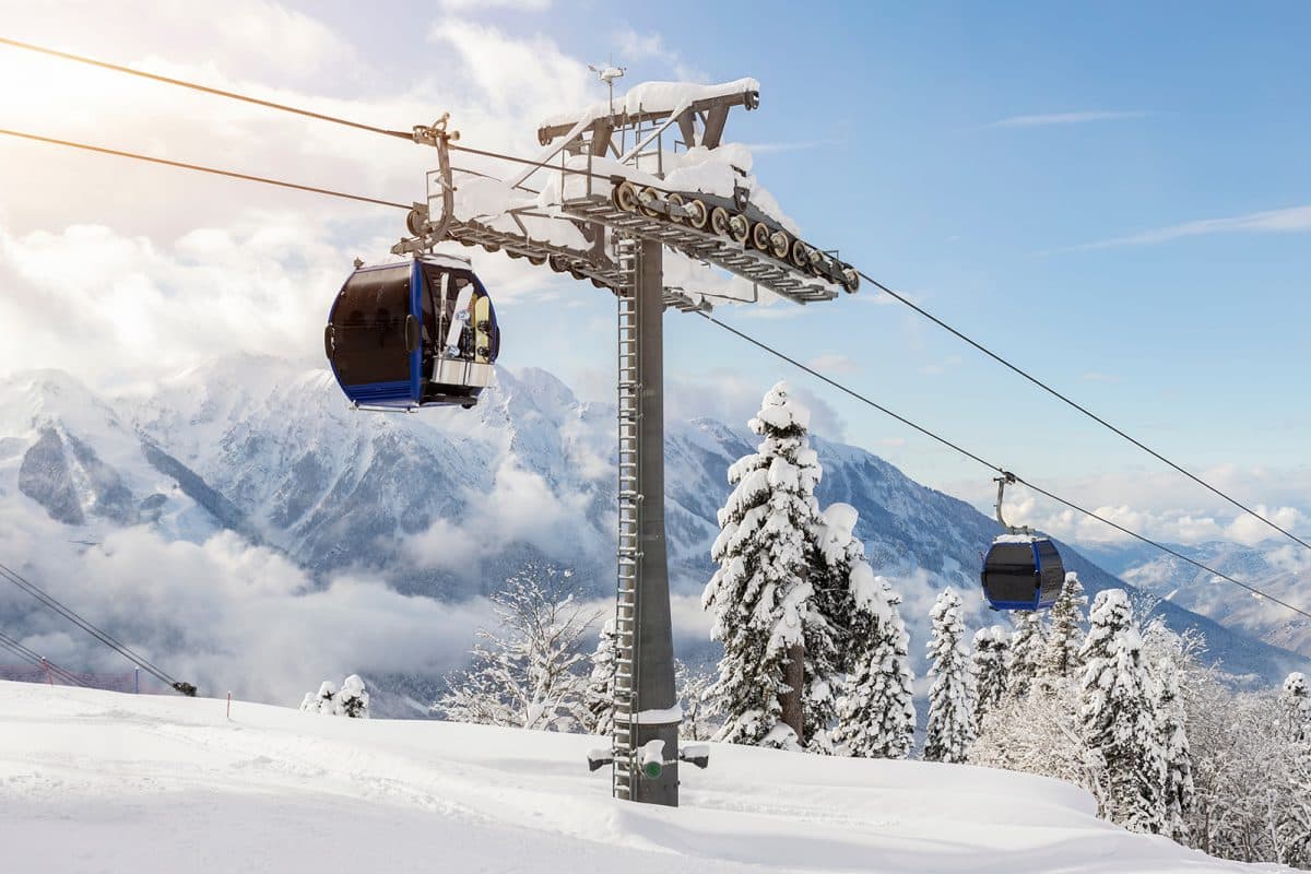 A ski gondola going up a snowy hillside